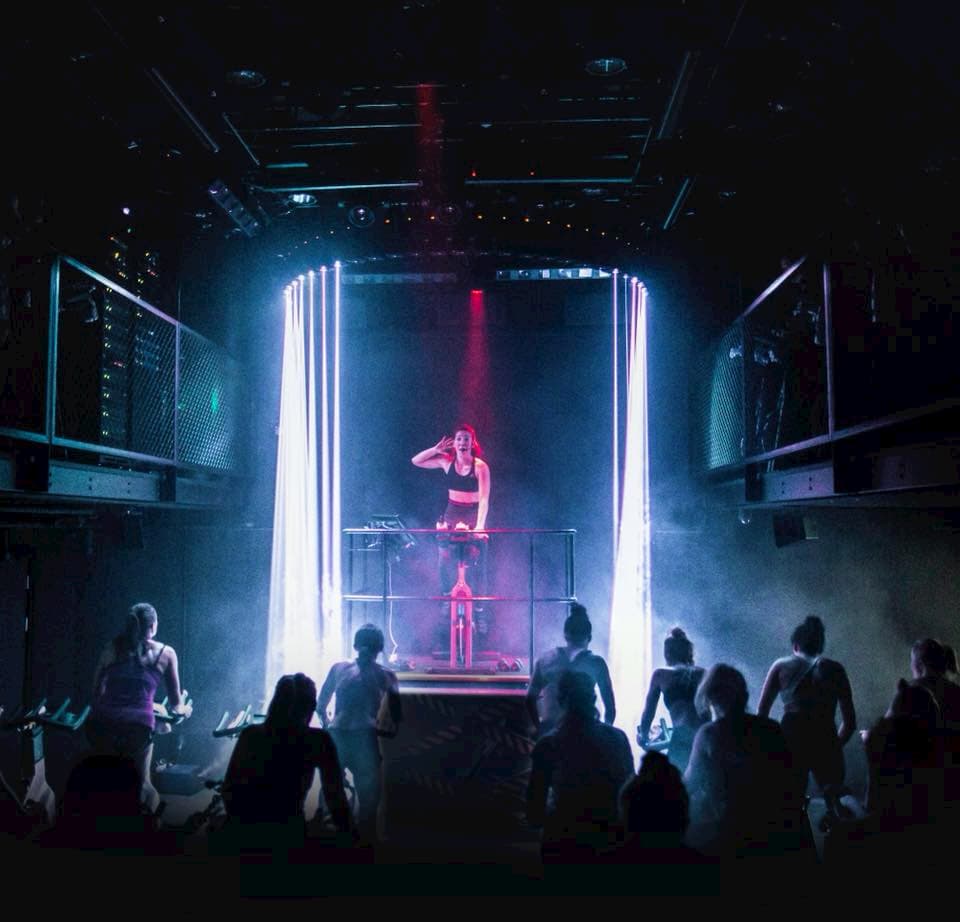 Spinning class with spotlights on the coach